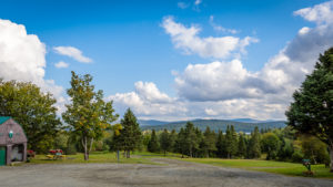 Countryside barn, meadow, trees, and distant mountains